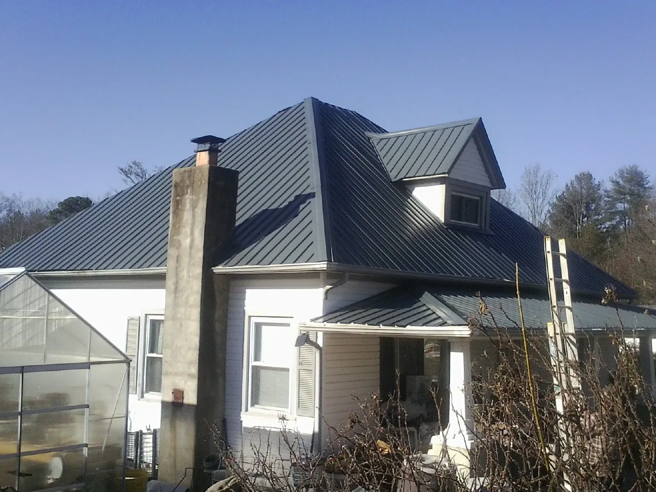 Dark blue standing seam metal roof on a white farmhouse with dormer — Slate & Tile Roof Repair by Roofing Brothers in Hoagland