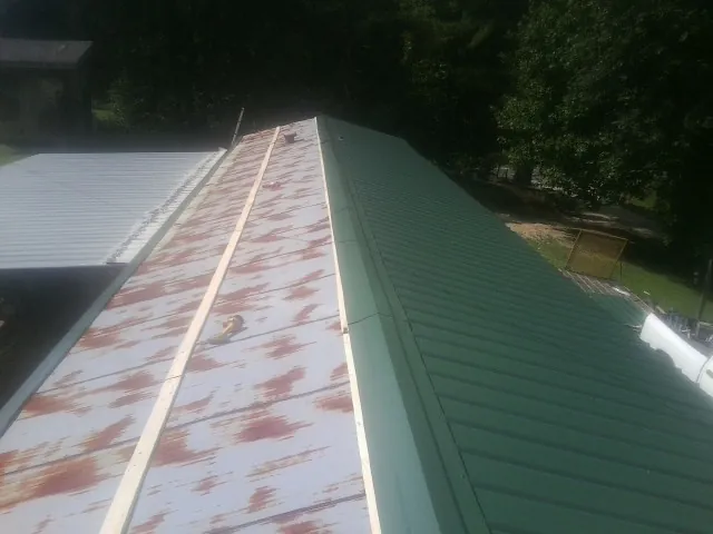 Old rusted panels beside newly installed green metal roofing — Wind Damage Roof Repair by Roofing Brothers in Hoagland