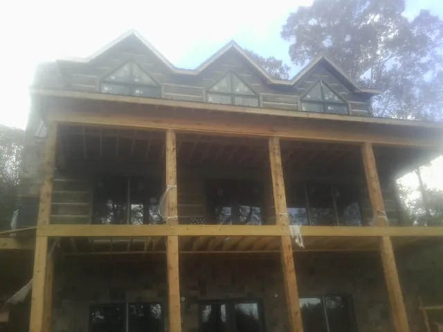 Dormers and porch framing on a large log home under construction — Roof Coating work by our crew in Hoagland