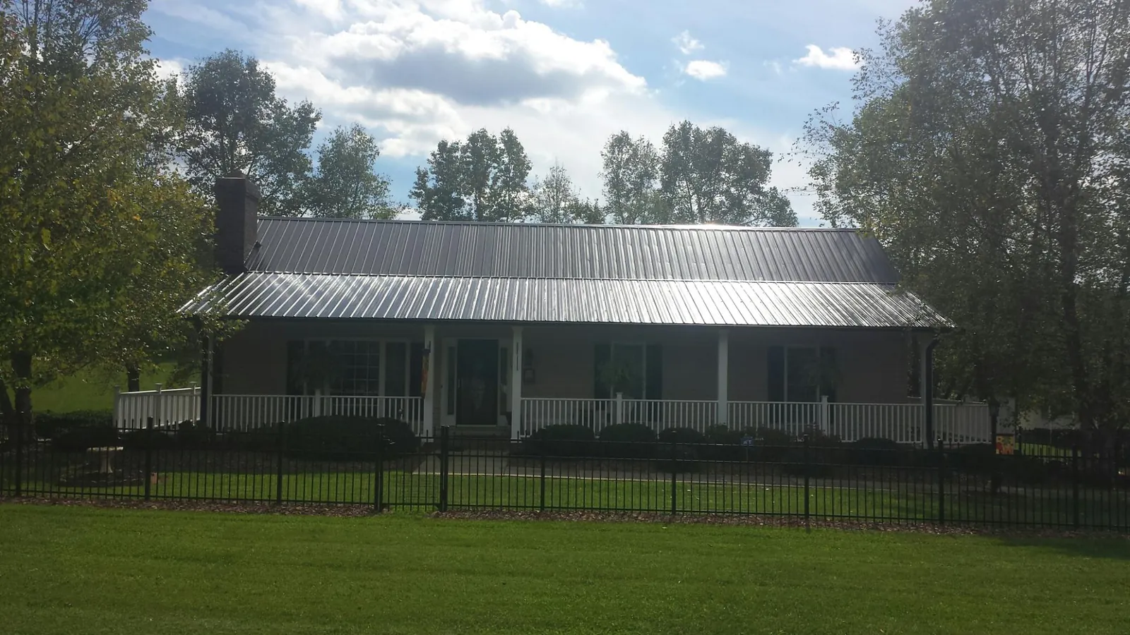 Gray metal roof on a brick ranch with a full width front porch — Gutter Guard Installation work by our crew in Hoagland