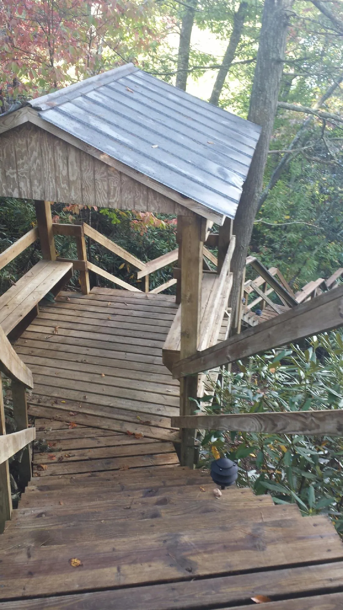 Metal roofed shelter over wooden steps on a wooded walkway — Skylight Repair & Installation work by our crew in Hoagland