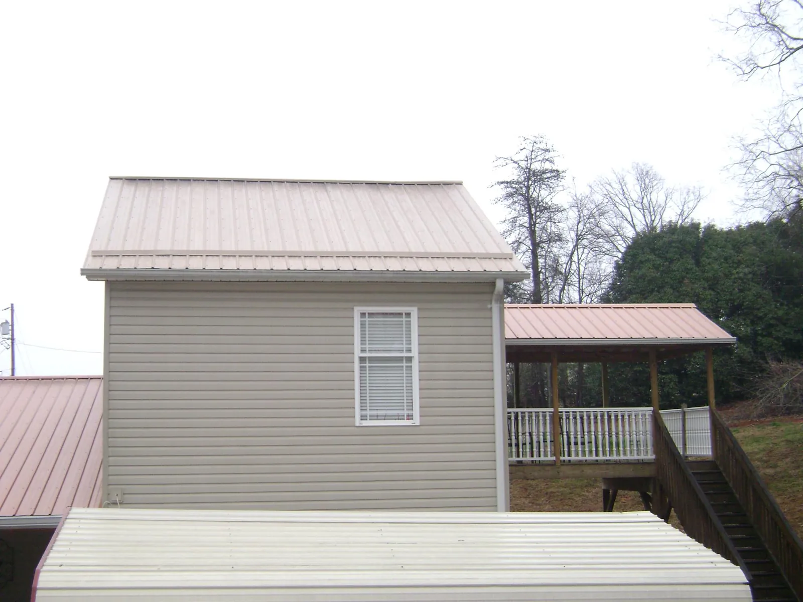 Tan metal roofs on a two story addition and attached porch, from a Roof Replacement job in Hoagland