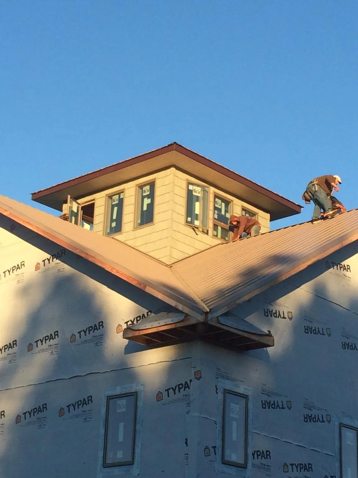 Roofers working around a rooftop cupola on a new metal roof at sunset — Roof Waterproofing in Hoagland by Roofing Brothers